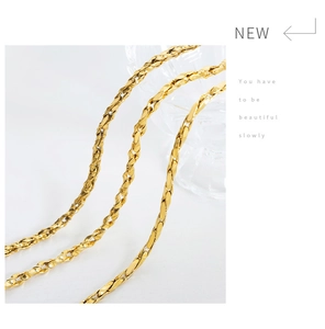 Detail of twisted flat gold plated necklaces with a high polish finish on white background
