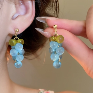 Detail of creative grape-shaped drop earrings with translucent resin beads and gold metal studs
