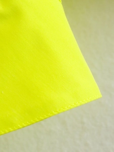 Détail du tissu tissé jaune néon montrant des coutures fines et une texture textile