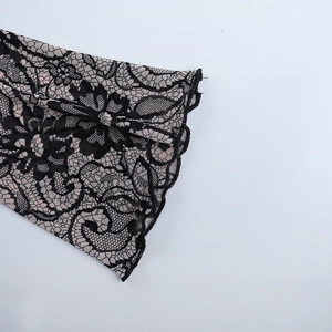 Detailed close-up of flared lace cuffs with black floral patterns over pink fabric
