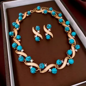 Vintage gold necklace and earrings set with turquoise beads and crystals in a jewelry tray