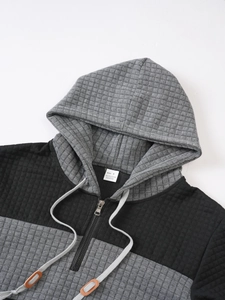 Detail of color-block hoodie featuring quilted grid texture and metal zipper closure