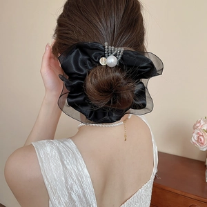 Detail of a black satin and organza scrunchie with white pearl and crystal accents
