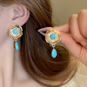 Detail of vintage flower earrings with turquoise stone drop and gold-plated floral design