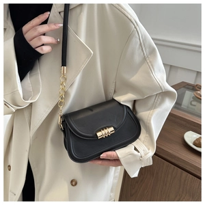 Detail of black leather crossbody bag featuring gold metal hardware and stitching