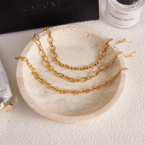 Detailed view of three 18k gold plated stainless steel chain styles on a stone tray