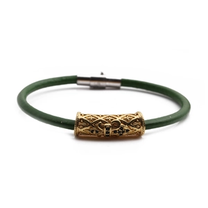 Macro shot of green leather bracelet featuring golden cylinder metal bead with filigree