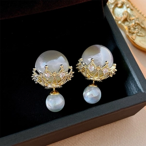 Detail of crown shaped pearl earrings with sparkling rhinestones and gold plating