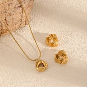 Elegant gold knot jewelry set with necklace and stud earrings on textured background