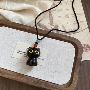 Close-up of black cat wood pendant with colorful beads and adjustable woven cord necklace
