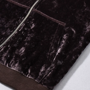 Close-up of dark brown velvet hoodie fabric texture with metal zipper and ribbed hem