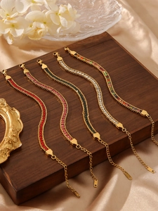 Detail of 18K gold-plated bracelets with colorful zircons on a dark wood stand