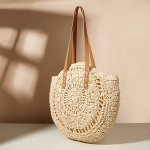 Minimalist beige woven round straw beach bag with brown leather straps under sun shadows
