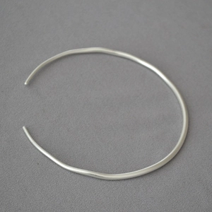 Macro shot of minimalist silver open choker featuring slender irregular curved lines