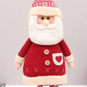 Close-up of a handmade knitted Santa Claus doll with red yarn and wooden button details