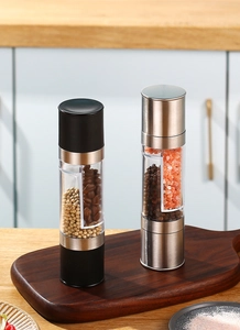 Close-up of dual-head salt and pepper grinders with visible windows on a wooden board