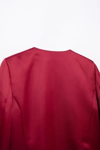 Detail shot of the back shoulder and collar on a glossy red satin Christmas top