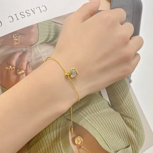 18k gold plated stainless steel heart necklace with shell inlay on a model's wrist