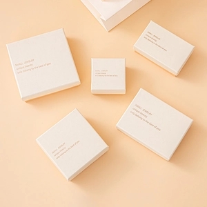 Flat lay of white textured paper jewelry boxes in various sizes on a soft pink backdrop