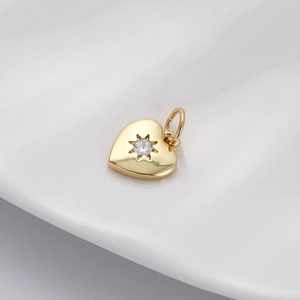 Macro detail of gold heart pendant with starburst zircon setting on white surface