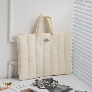 Close-up of quilted cream laptop sleeve with top handles and secure zipper closure