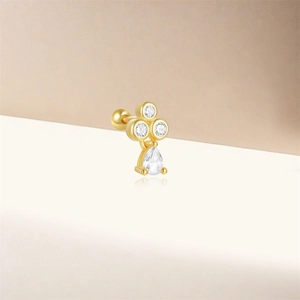 Macro detail of gold earring featuring three round zircons and a pear-cut drop stone