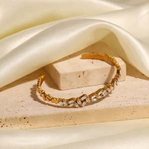 Bracelet jonc ouvert élégant en acier titane doré avec zircons sur fond de pierre beige