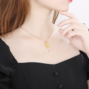 Primo piano della collana con ciondolo Bilancia dorato indossata su top nero