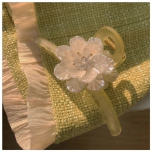 Dettaglio di un fermaglio per capelli giallo satinato con un grande fiore bianco perlato