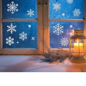 Silver glitter snowflake window decals set on frosted glass with a warm festive lantern