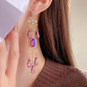 Close-up of pink crystal tassel earrings with sparkling rhinestones and golden details