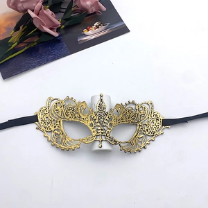 Detailed view of a gold lace masquerade mask with black ribbons on a white background