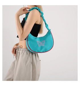 Détail du sac bandoulière croissant vert avec broderie papillon et bandoulière à volants