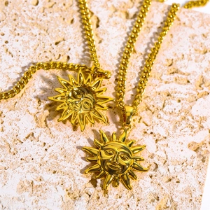 Detail of two vintage gold sun face necklaces on a textured stone surface