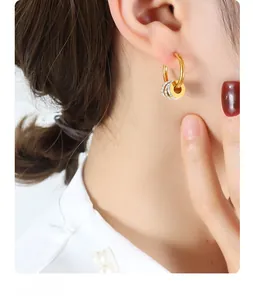 Details von eleganten goldenen Creolen mit drei Anhängern und Zirkonen am Modell