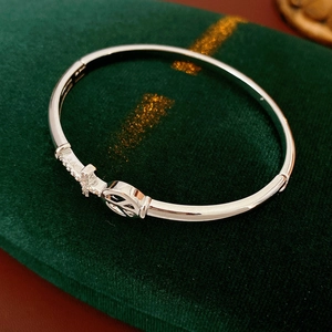 Detail of silver bangle featuring rhinestone cross and peace sign charms on velvet