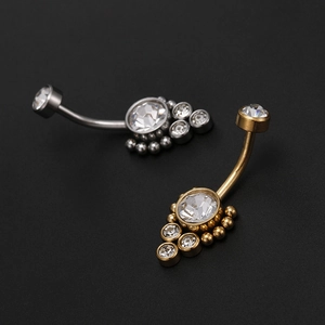 Macro shot of silver and gold belly rings with round cubic zirconia and polished beads