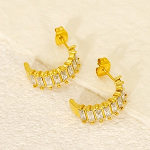 Detail of C-shaped gold earrings set with rectangular cubic zirconia stones