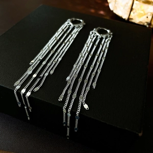 Detail of silver long chain tassel earrings with sequins on a black jewelry box