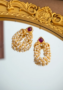 Detail of vintage gold earrings with purple gemstone and tiered white pearl tassels