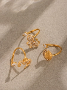 Detail of gold octopus, seahorse and shell rings with cubic zirconia inlay