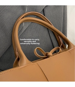 Detail of comfortable brown leather handles and tie closure on a woven tote bag