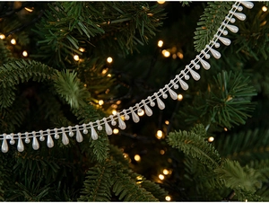 Close-up of cream white pearl teardrop garland draped on a green Christmas tree branch