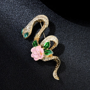 Macro shot of gold snake brooch with pink enamel flower and rhinestones on black
