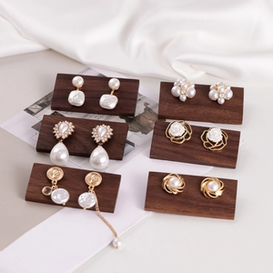 Walnut wood earring display stand with pearl studs and gold floral earrings collection