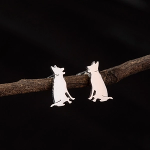 Polished stainless steel German Shepherd silhouette stud earrings on a dark wood branch