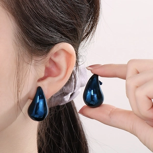 Polished dark blue water drop earrings made of stainless steel shown on a model