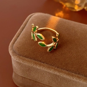 Detail of a vintage golden ring with green enamel leaves on brown velvet display