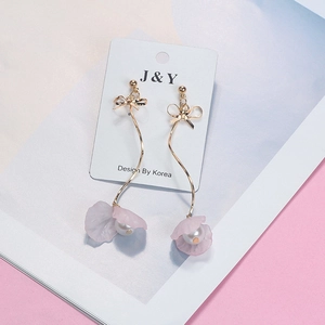 Detail of long gold drop earrings with bow accents, pink petals, and pearls on a card