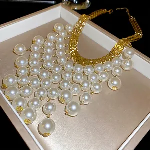 Statement necklace featuring woven gold chains and layered pearls on a jewelry display tray